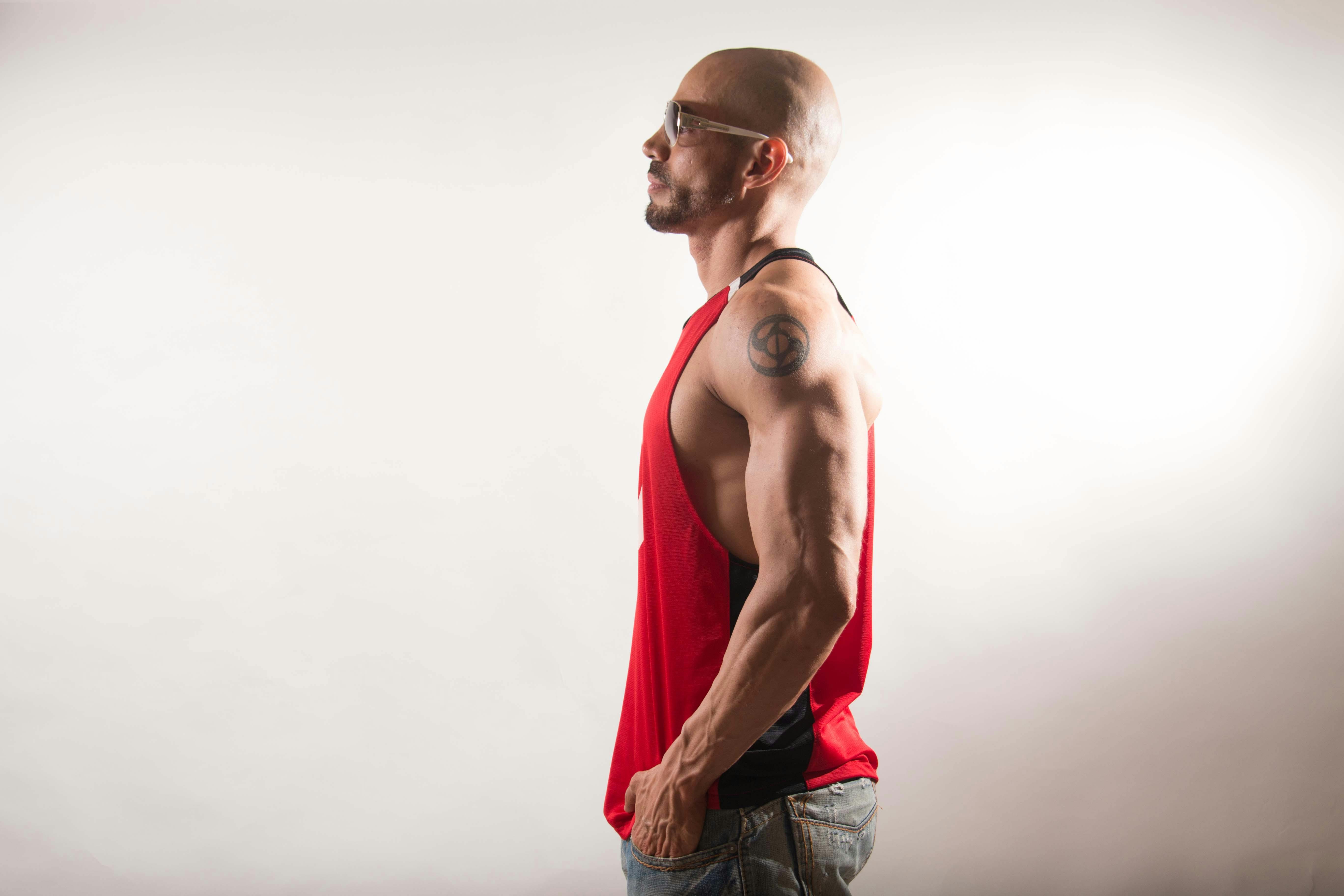 pexels-photo-13459875-13459875 Profile of a fit, muscular man wearing a red tank top in a studio setting.
